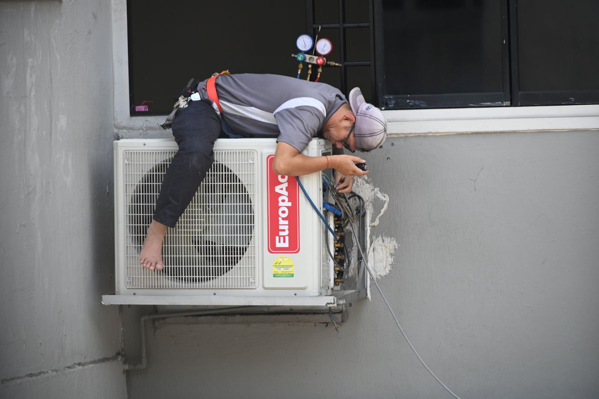 Technician servicing a wall-mounted ductless air conditioning unit.